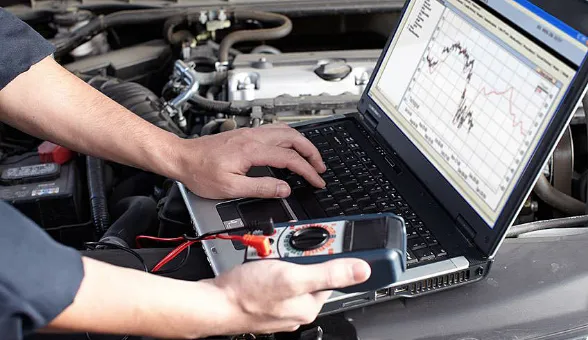 Fehlerdiagnose am Laptop mit Messgerät im Motorraum