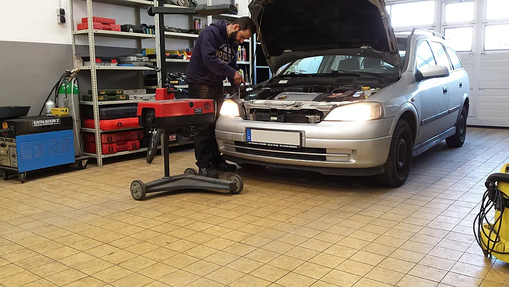 Blick in die Werkstatt: Ein Mechaniker arbeitet an einem Opel Astra mit geöffneter Motorhaube
